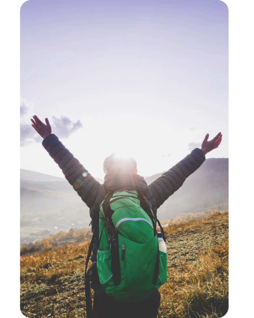 A person with a green backpack standing on a mountain with arms raised toward the sunrise, symbolizing personal growth, freedom, hope, mindfulness, and new beginnings.